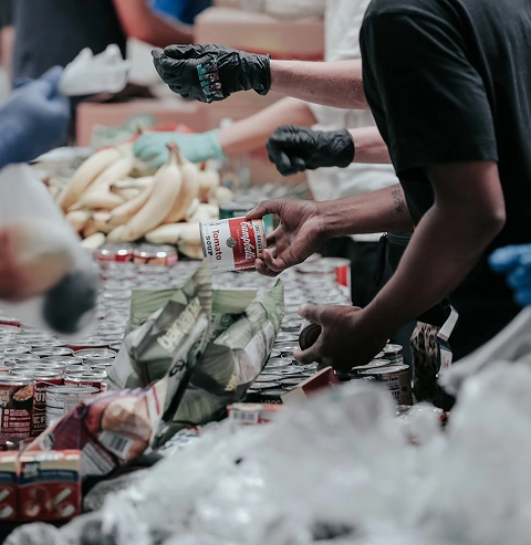 Volunteers in black gloves distributing food donations to families in need
